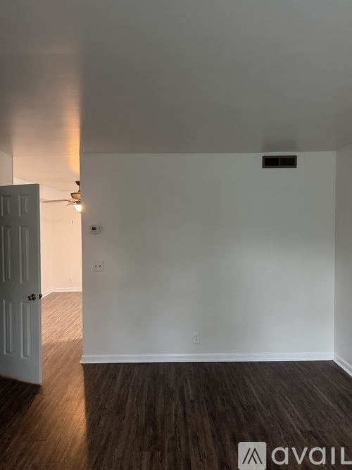 A room with a white door and a wooden floor.