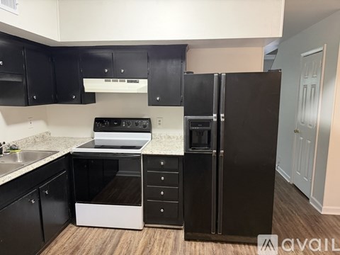 A kitchen with black cabinets and a white stove top oven.