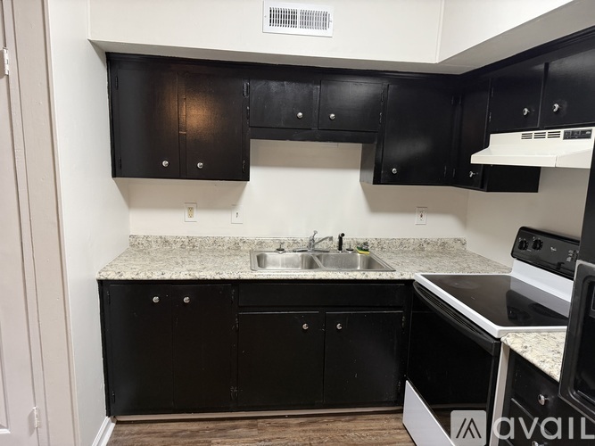 A kitchen with black cabinets and a granite countertop.