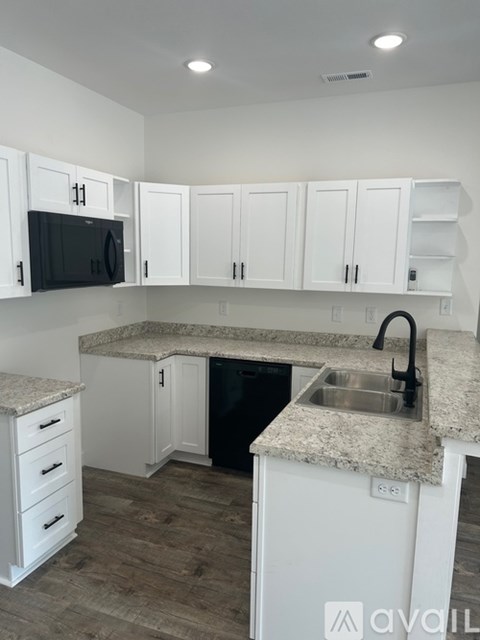 A kitchen with white cabinets and a granite countertop.