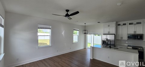 A spacious kitchen with white cabinets and a dark countertop.