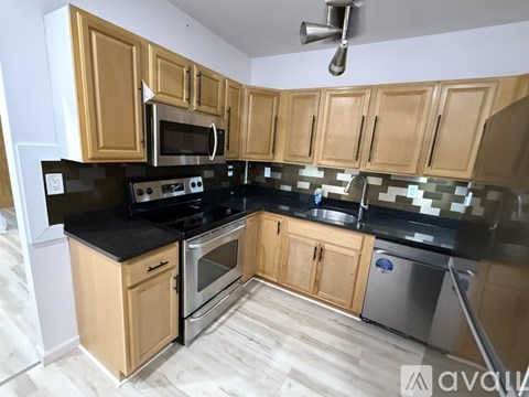A kitchen with wooden cabinets and black countertops.