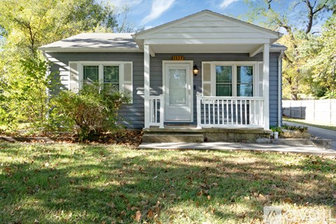 A small house with a porch and a sign on the front door.