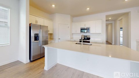 A kitchen with white cabinets and a stainless steel refrigerator.