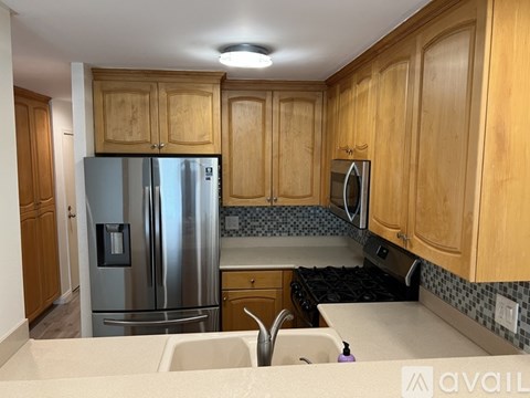 A kitchen with wooden cabinets and a stainless steel refrigerator.