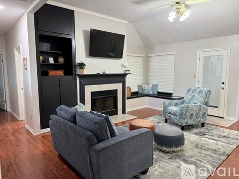 A living room with a grey couch, a fireplace, and a television mounted on the wall.