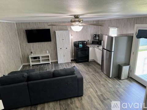 A living room with a black couch and a television on the wall.
