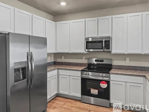 A kitchen with white cabinets and a stainless steel refrigerator.