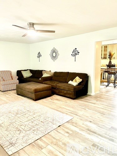 A living room with a brown couch and a rug.