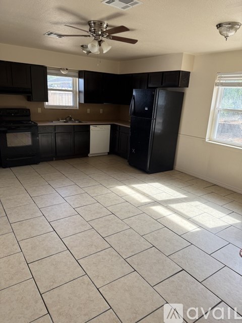 A kitchen with black cabinets and a ceiling fan.