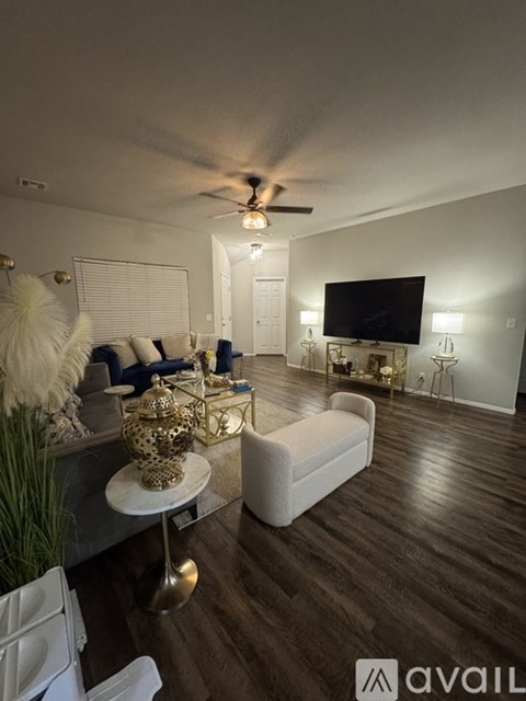 A living room with a white couch, a television, and a ceiling fan.