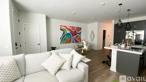 A living room with a white couch and a colorful painting on the wall.