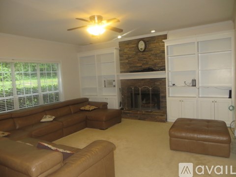 A living room with a brown leather couch and a stone fireplace.