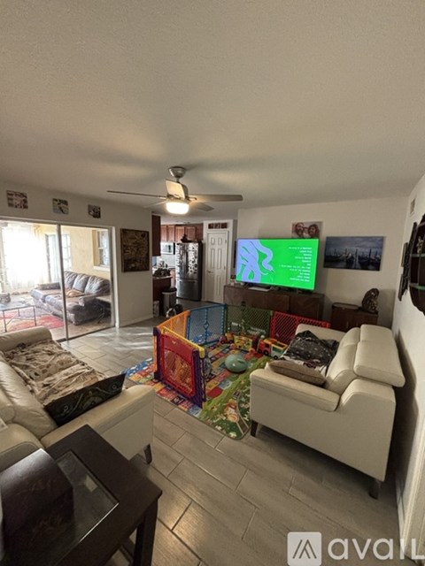 A living room with a white couch and a television displaying a green screen.