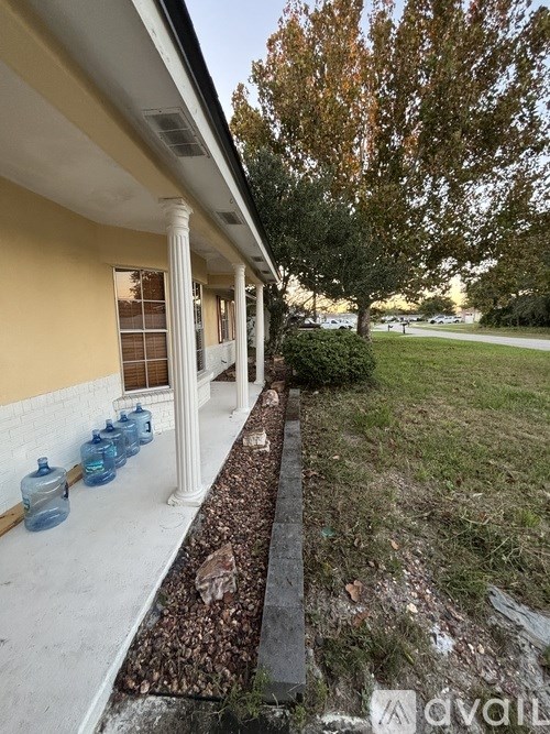A house with a porch and a tree in the background.