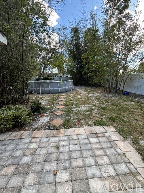 A backyard with a brick patio and a chain link fence.