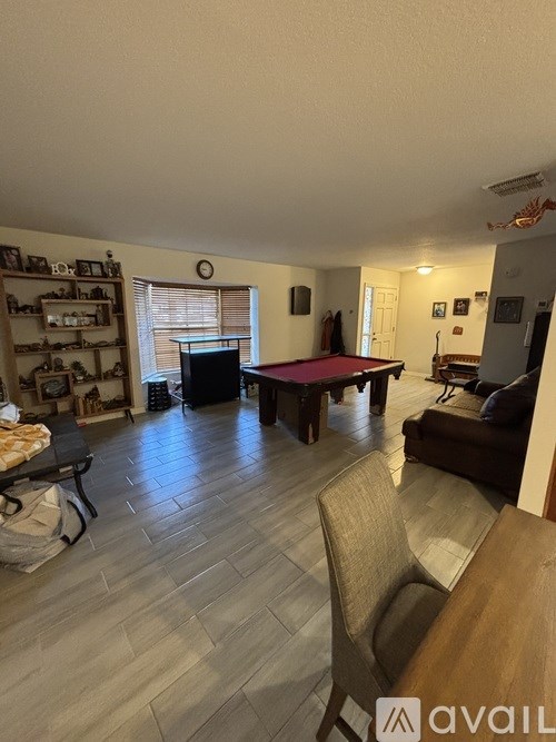 A living room with a pool table and a couch.
