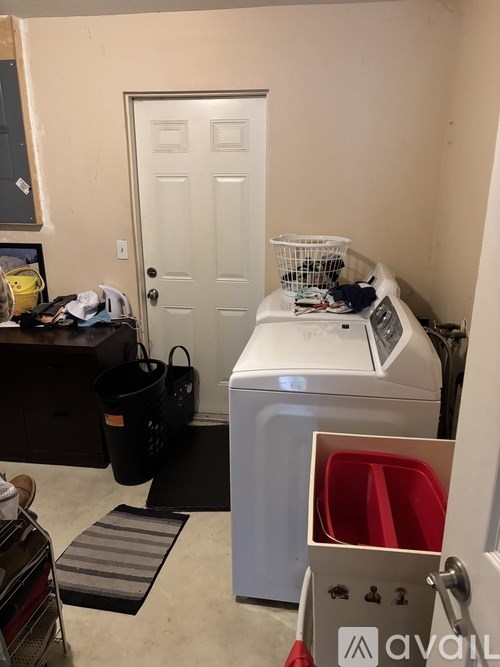 A small room with a washer and dryer, a door, and a mat on the floor.