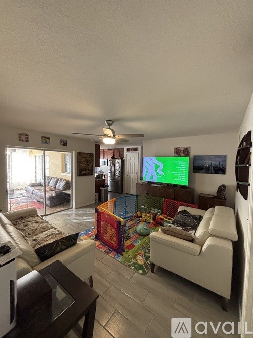 A living room with a white couch and a television on the wall.