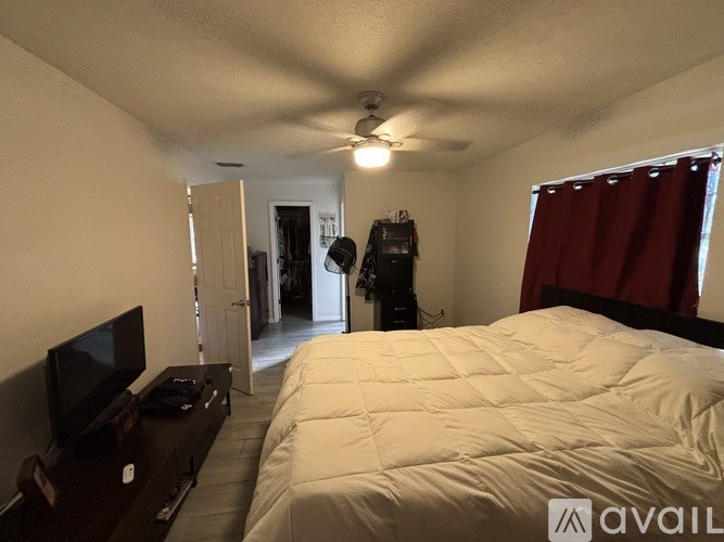 A bedroom with a large bed, a television, and a ceiling fan.