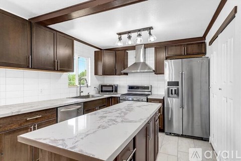 A kitchen with brown cabinets and a marble countertop.