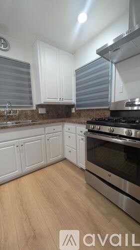 A kitchen with white cabinets and a stainless steel stove.