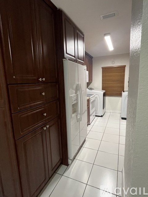 A kitchen with brown cabinets and a white refrigerator.