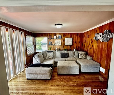 A living room with a grey couch and a wooden wall.