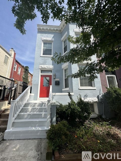 A blue house with a red door and white stairs leading up to it.