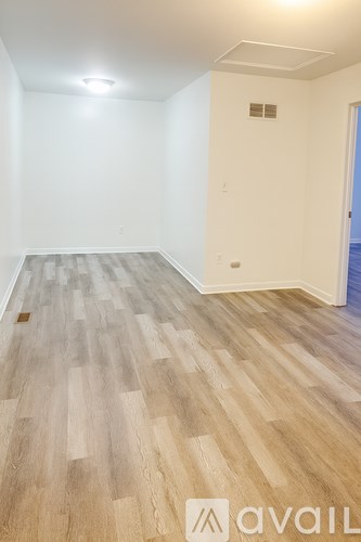 A room with wooden flooring and a white wall.