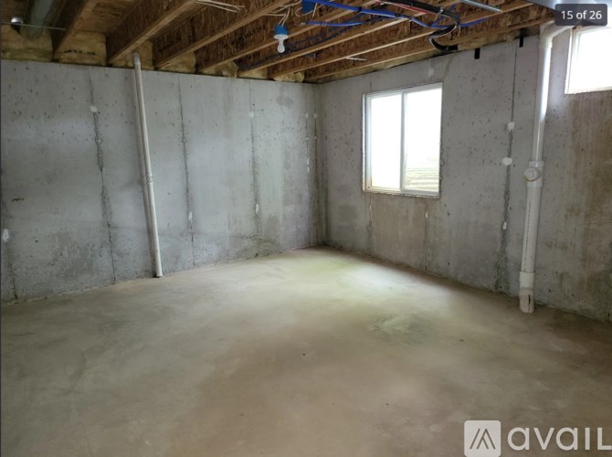 A room under construction with exposed ceiling and pipes.