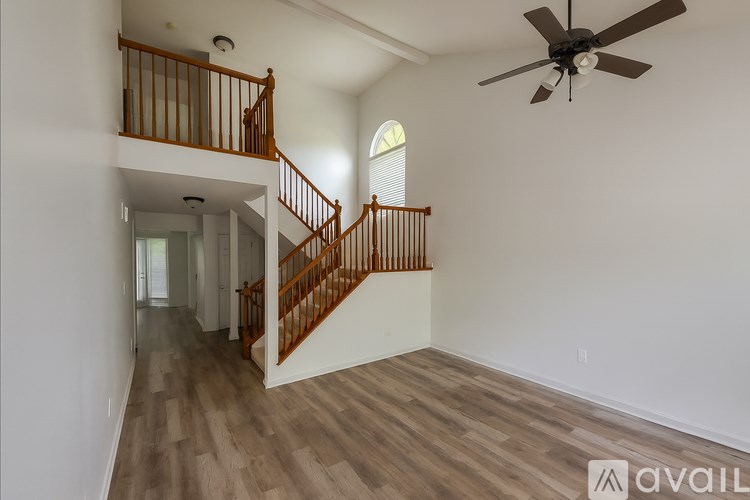 A spacious room with a wooden staircase and a ceiling fan.