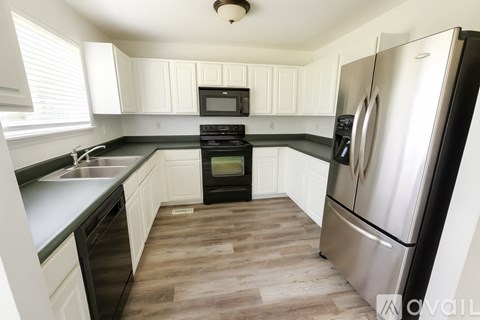 A kitchen with a black stove top oven and a black refrigerator.