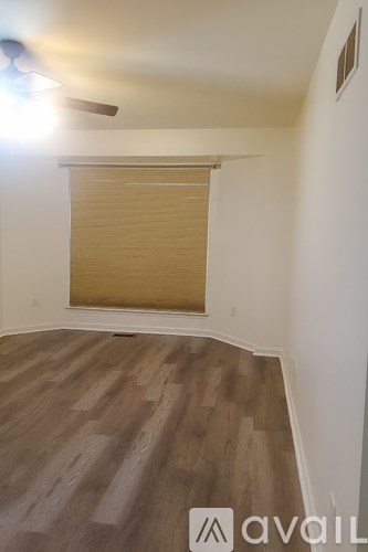 A room with wooden flooring and a window with blinds.