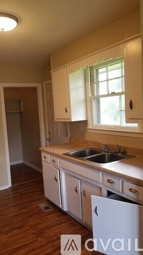 A kitchen with white cabinets and a window above the sink.