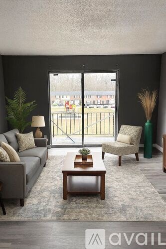 A living room with a grey couch, a wooden coffee table, and a chair with a green vase.