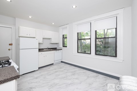 A kitchen with white cabinets and a marble floor.