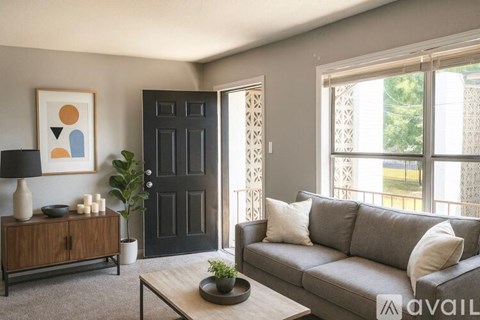 A living room with a grey couch, a wooden cabinet, a black door, and a painting on the wall.