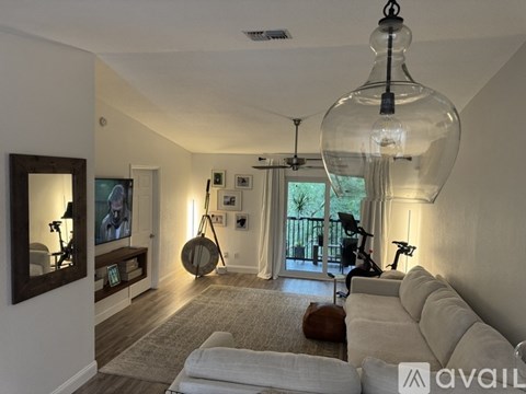 A living room with a white couch and a hanging light fixture.
