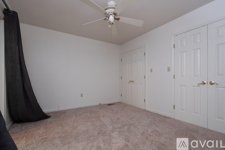 A room with a ceiling fan and two doors.