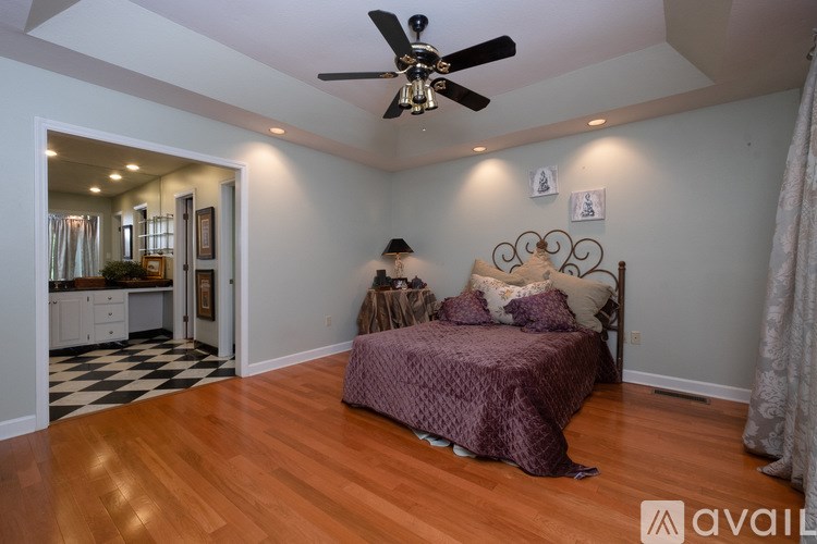 A bedroom with a bed, a ceiling fan, and a mirror.