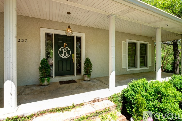 A house numbered 222 with a green door and a hanging light fixture.