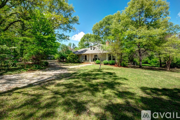 A house with a driveway and trees in front of it.