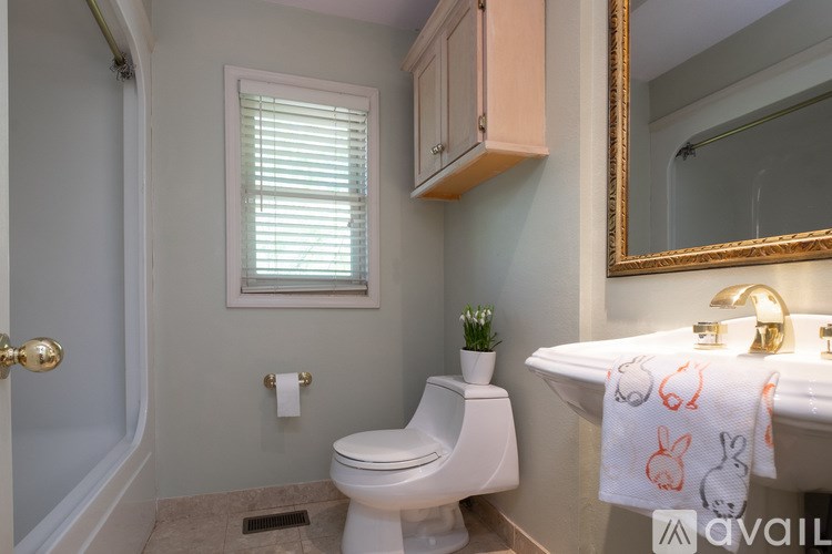 A bathroom with a toilet, sink, and a window.