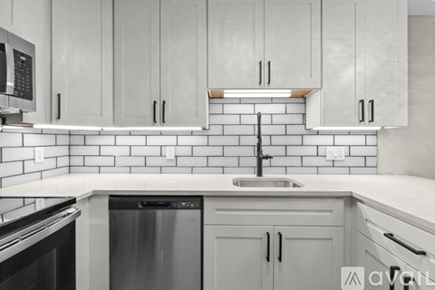 A kitchen with white cabinets and a black and white tiled backsplash.