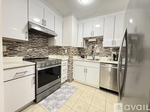 A kitchen with white cabinets and a stone backsplash.