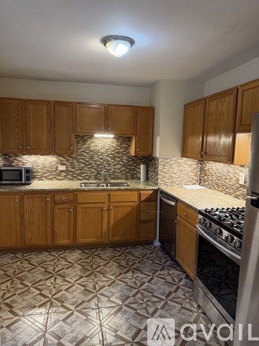 A kitchen with wooden cabinets and a patterned tile floor.