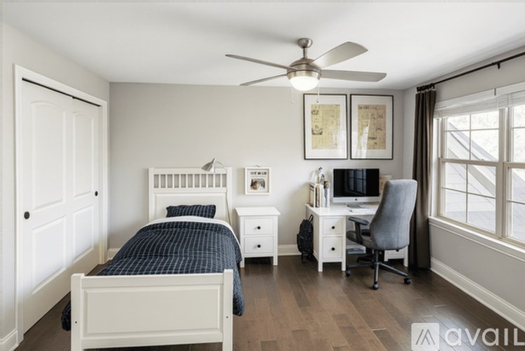 A bedroom with a bed, desk, and chair.