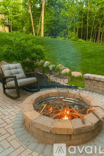 A fire pit with a fire burning in it and a chair next to it.