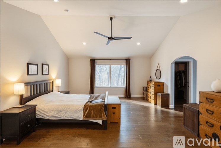 A bedroom with a large bed and a ceiling fan.